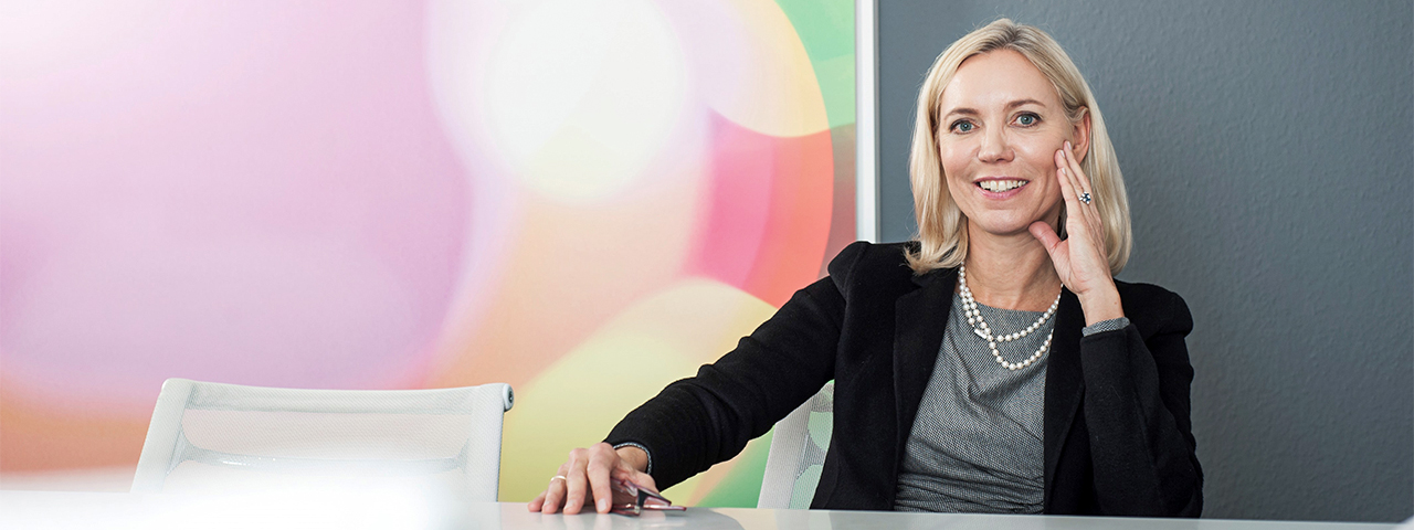 Header_Kontakt Dr. Anke Nienkerke-Springer sitzt lächeln an einem Tisch